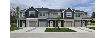 A grey and black two story house with a tree in front.