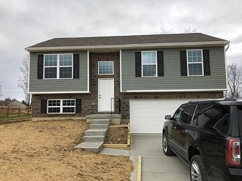 A grey house with a black car parked in front.