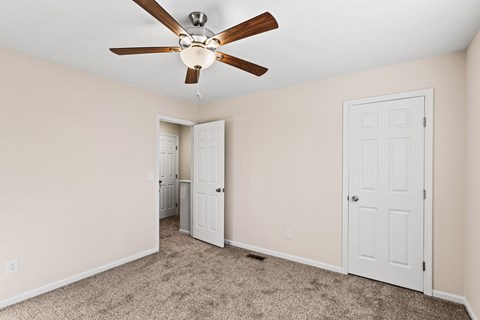 A room with a ceiling fan and carpeted floor.