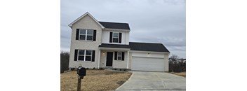 A two-story house with a garage and a mailbox in front.