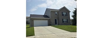 A two-story house with a garage door and a driveway.