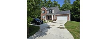A black car is parked in front of a brick house.