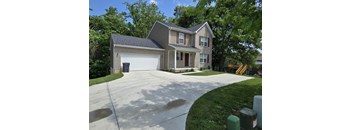 A two-story house with a garage and a driveway.