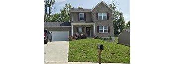 A house with a grey garage door and a grey car parked in front.