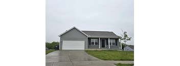 A grey house with a black door and a white garage door.