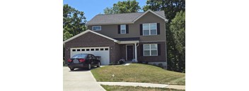 A black car is parked in front of a two-story house.