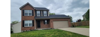 a brick house with a garage door and a lawn