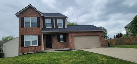 a brick house with a garage door and a lawn