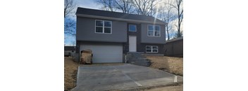 A house with a grey garage door and a brown box on the ground.