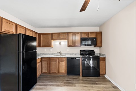 A kitchen with black appliances and wooden cabinets.