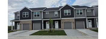 A grey house with a tree in front.