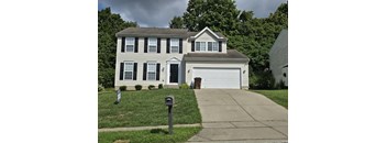 A two-story house with a garage and a mailbox in front.