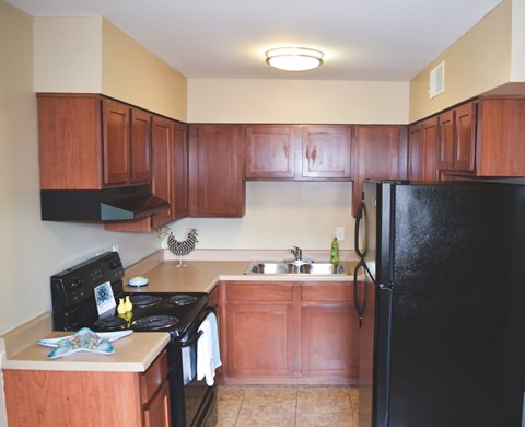 A kitchen with wooden cabinets and black appliances.
