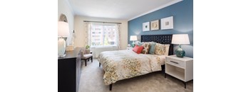 A bedroom with a large bed and a window with curtains.