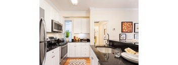 A modern kitchen with black countertops and white cabinets.