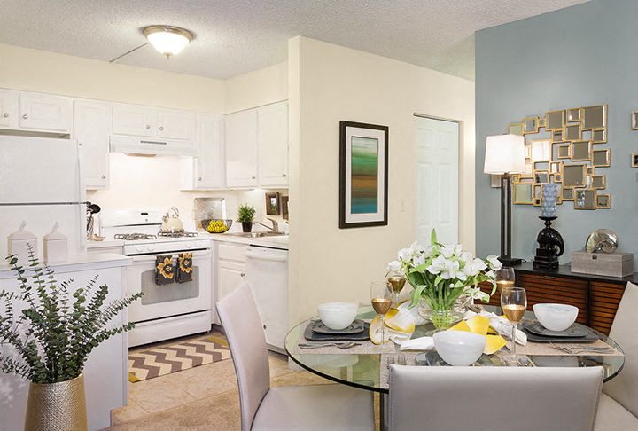 A modern kitchen with a dining table set for two.