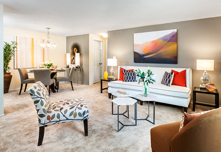 A living room with a white couch and a painting on the wall.