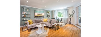 A living room with a grey couch, a white coffee table, and a painting on the wall.