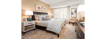 A bedroom with a bed, nightstand, and chair.
