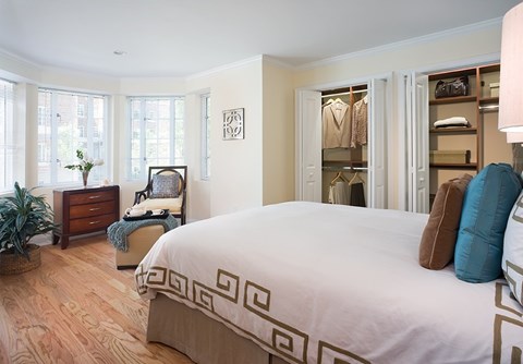 A bedroom with a large bed and a chair with a blanket on it.