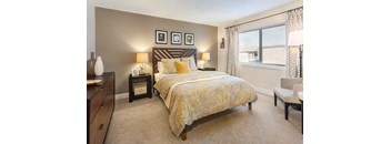 A bedroom with a bed, nightstands, and a chair.