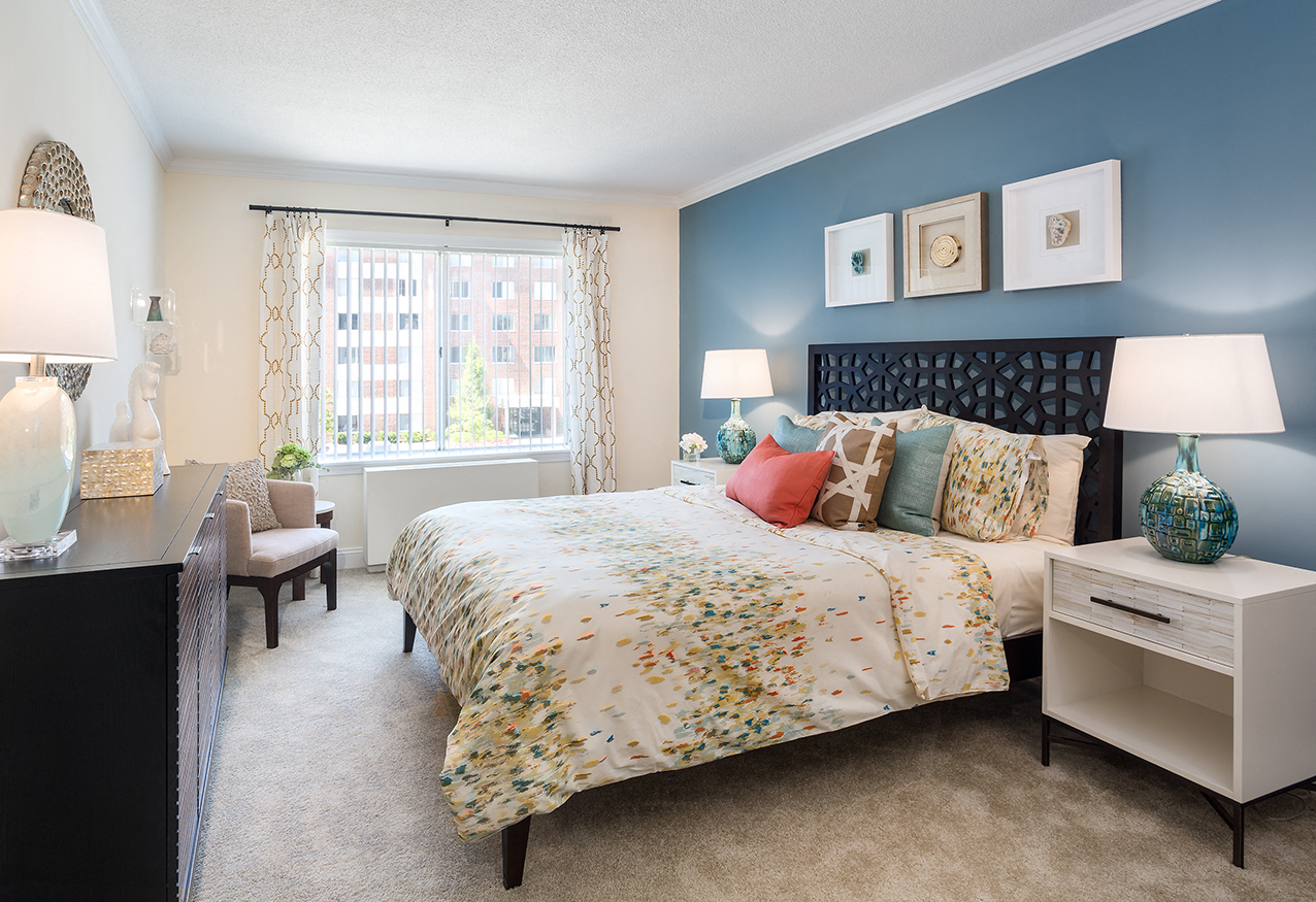A bedroom with a large bed and a window with curtains.