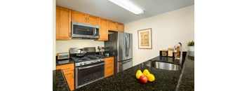 A kitchen with black granite countertops and wooden cabinets.