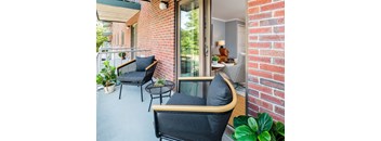 A patio with a black chair and a table with a plant on it.
