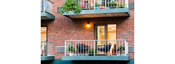 A red brick building with a balcony and plants.