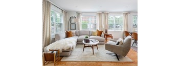 A living room with a grey couch, a white fur throw, and a coffee table.