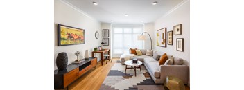A living room with a couch, a coffee table, a rug, and a painting on the wall.
