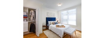 A bedroom with a bed, nightstand, and a window with curtains.