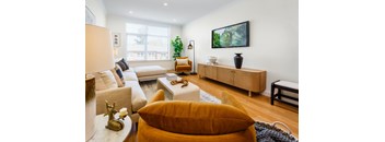 A living room with a white couch, a yellow pillow, and a wooden cabinet.