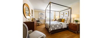 A bedroom with a four poster bed and a chair.