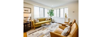 A living room with a green sofa, brown leather chairs, and a glass coffee table.