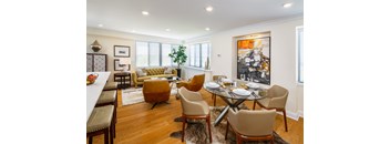 A dining room with a glass table surrounded by chairs.