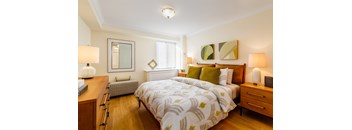A bedroom with a bed, nightstand, and a mirror.