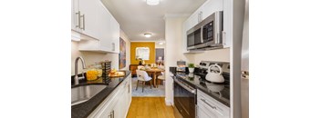 A kitchen with a black counter top and white cabinets.