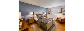 A bedroom with a bed, two nightstands, and a chair.