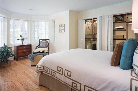 A bedroom with a large bed and a chair by the window.