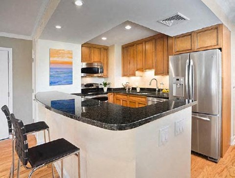 A kitchen with a black counter top and stainless steel appliances.