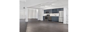 A modern kitchen with dark wood floors and stainless steel appliances.