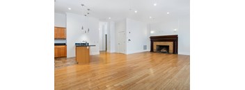 A spacious room with a fireplace and wooden floors.