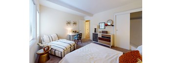 A bedroom with a bed, a chair, and a dresser.