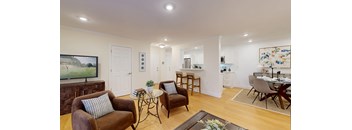 A living room with brown chairs and a glass table.