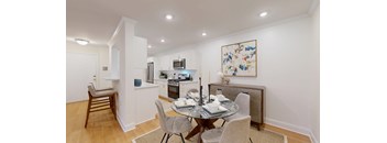 A dining room with a table set for two and a painting on the wall.