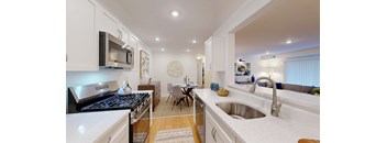 A modern kitchen with white cabinets and a black stove top.
