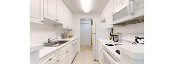 A white kitchen with a sink, stove, and refrigerator.
