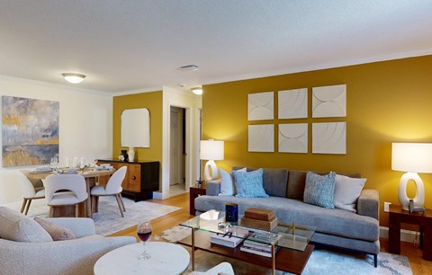 A living room with a grey couch and a painting on the wall.