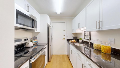 A kitchen with white cabinets and black countertops.